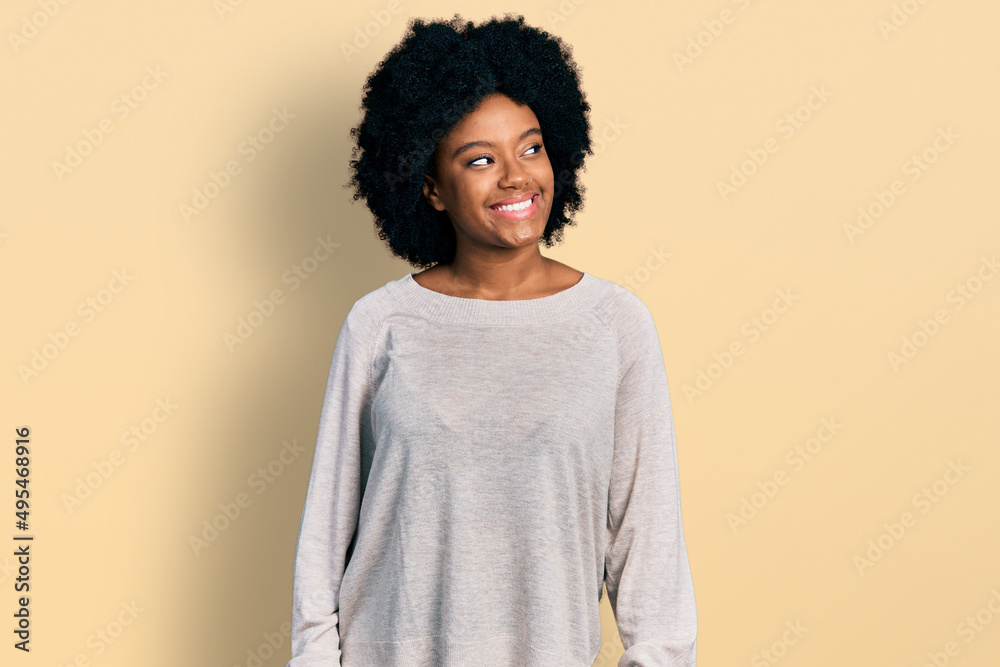 Young african american woman wearing casual clothes looking away to side with smile on face, natural expression. laughing confident. Young african american woman wearing casual clothes looking away to side with smile on face, natural expression. laughing confident.