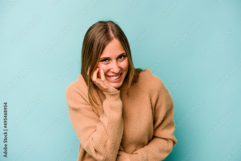 Young caucasian woman isolated on blue background laughs happily and has fun keeping hands on stomach. Young caucasian woman isolated on blue background laughs happily and has fun keeping hands on stomach.