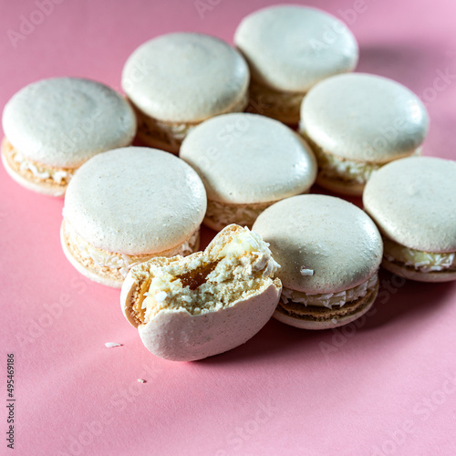 Fresh white macaroons with caramel and coconut on a pink background