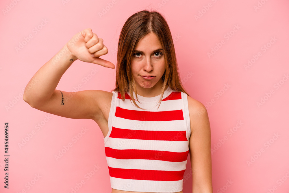 Young caucasian woman isolated on pink background showing thumb down and expressing dislike. Young caucasian woman isolated on pink background showing thumb down and expressing dislike.