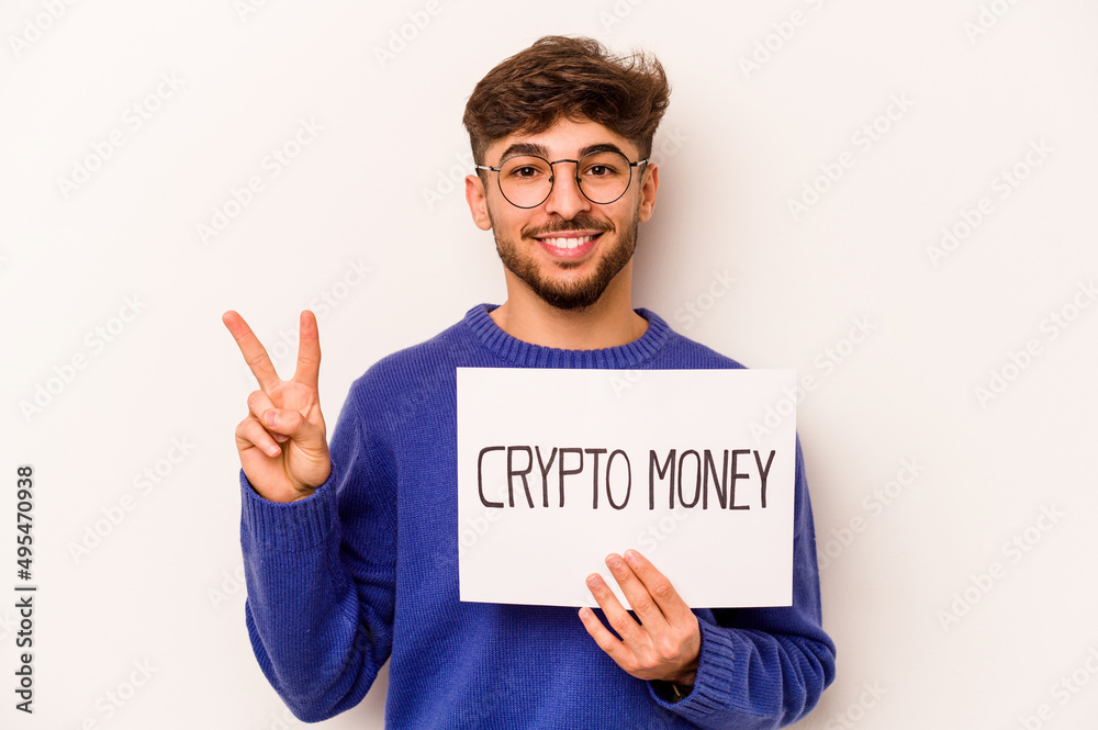 Young hispanic man holding a crypto money placard isolated on white background showing number two with fingers. Young hispanic man holding a crypto money placard isolated on white background showing number two with fingers.