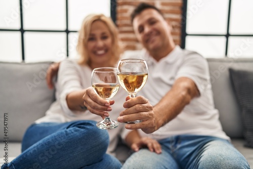 Middle age man and woman hugging each other toasting with champagne at home