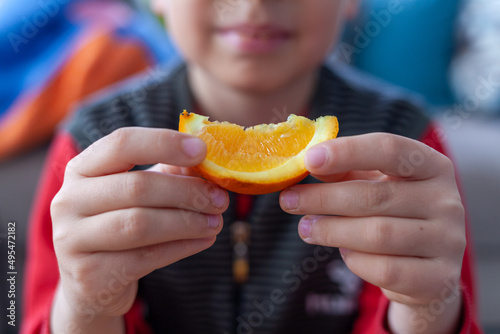A boy holding a slice of orange.