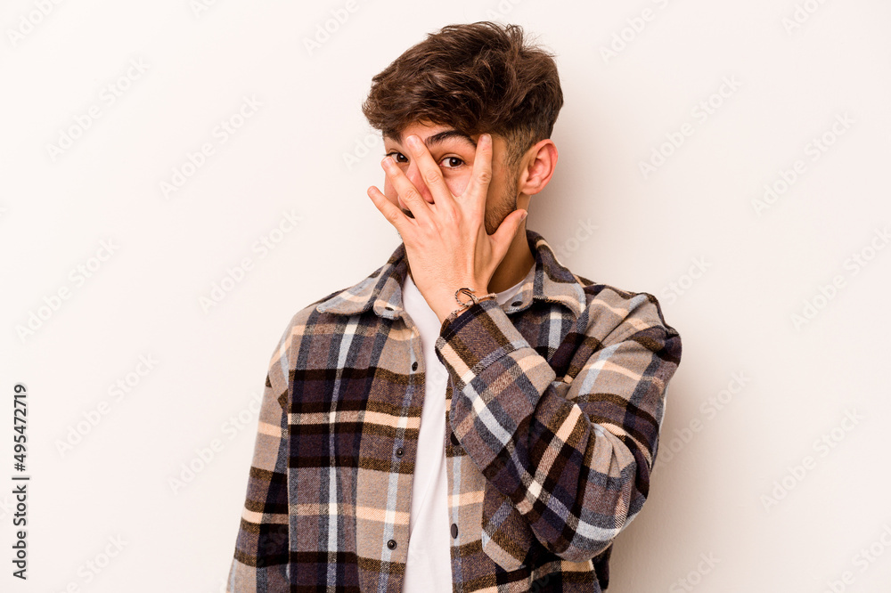 Young hispanic man isolated on white background blink at the camera through fingers, embarrassed covering face. Young hispanic man isolated on white background blink at the camera through fingers, embarrassed covering face.