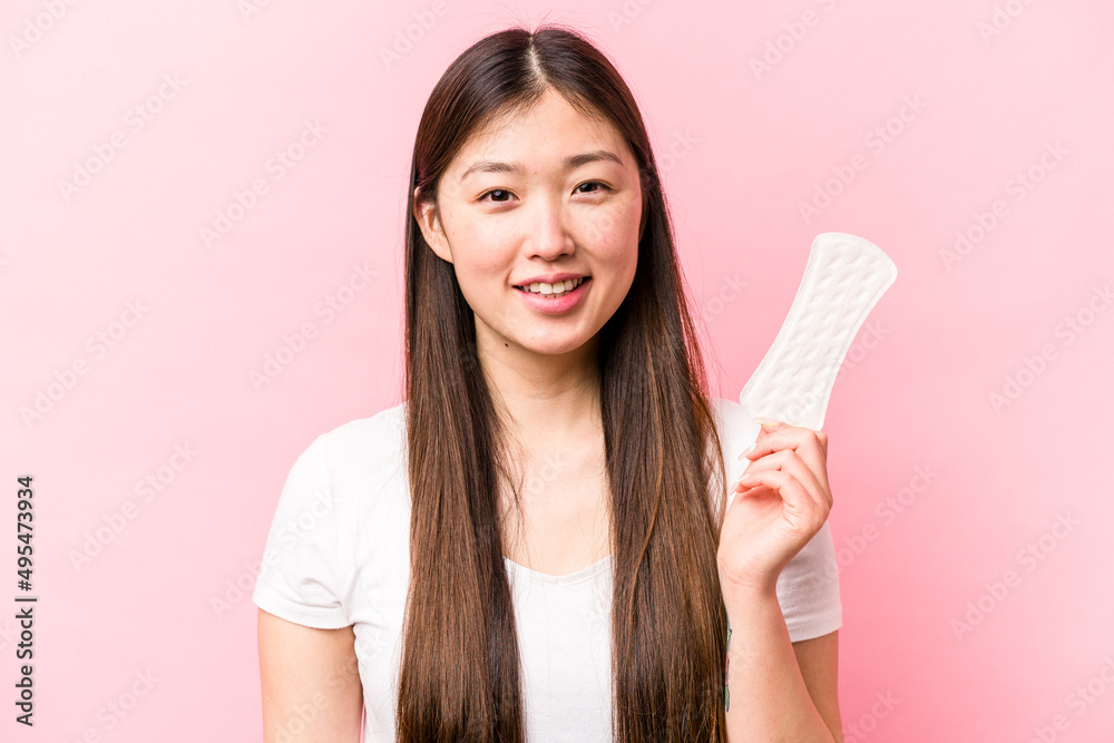 Young asian woman holding sanitary napkin isolated on pink background happy, smiling and cheerful. Young asian woman holding sanitary napkin isolated on pink background happy, smiling and cheerful.