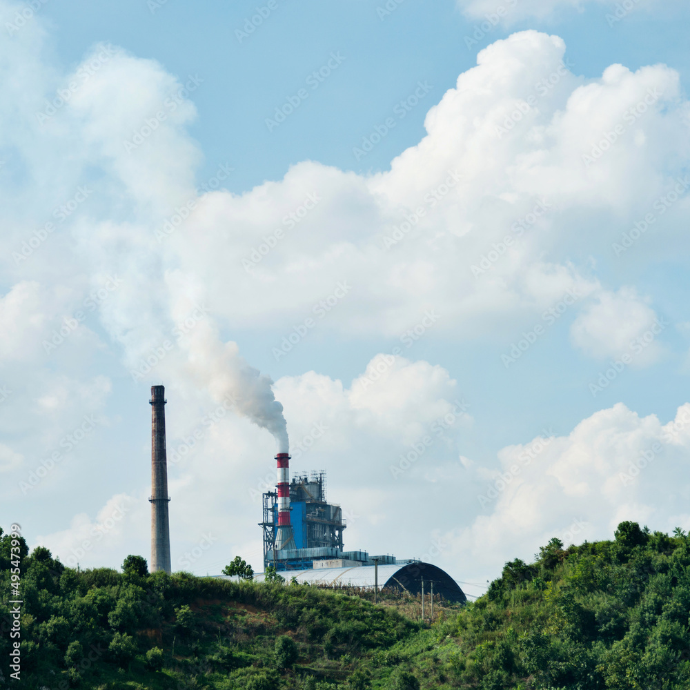 Factory chimneys smoke rising into the sky at green hill Factory chimneys smoke rising into the sky at green hill