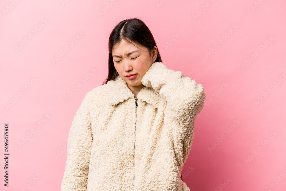 Young Chinese woman isolated on pink background massaging elbow, suffering after a bad movement. Young Chinese woman isolated on pink background massaging elbow, suffering after a bad movement.