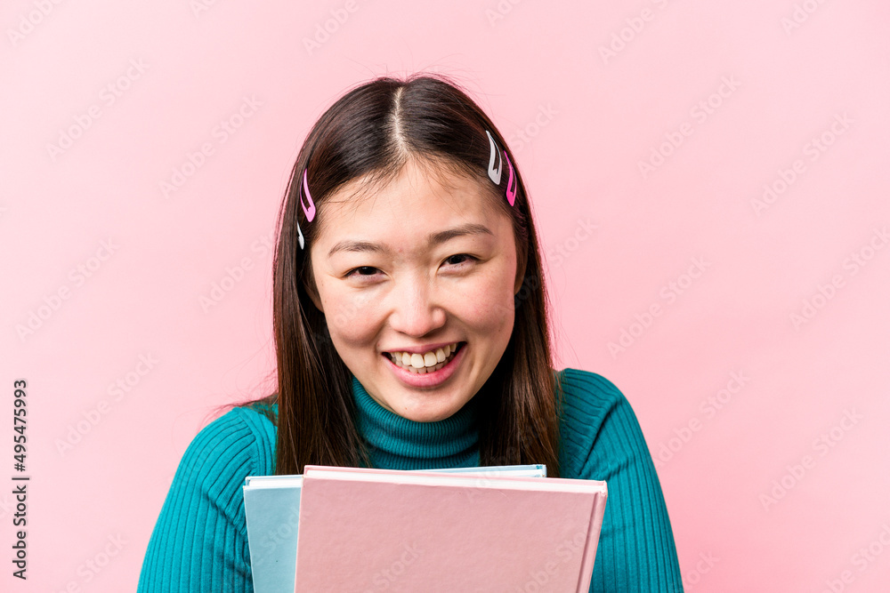 Young asian student woman holding books isolated on pink background Young asian student woman holding books isolated on pink background