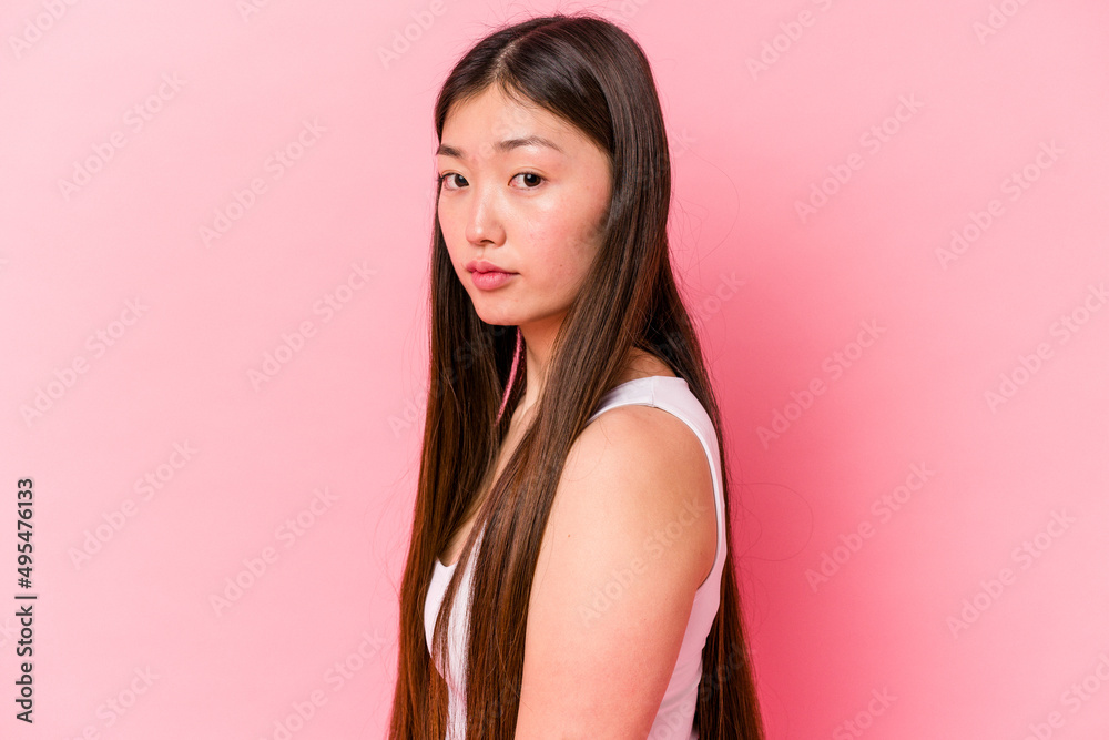 Young asian woman sitting on pink background Young asian woman sitting on pink background