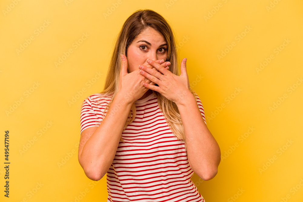 Young caucasian woman isolated on yellow background covering mouth with hands looking worried. Young caucasian woman isolated on yellow background covering mouth with hands looking worried.