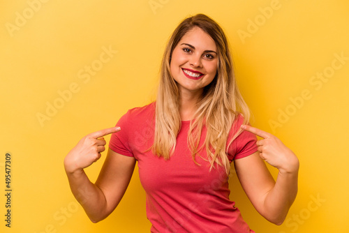 Young caucasian woman isolated on yellow background points down with fingers, positive feeling.