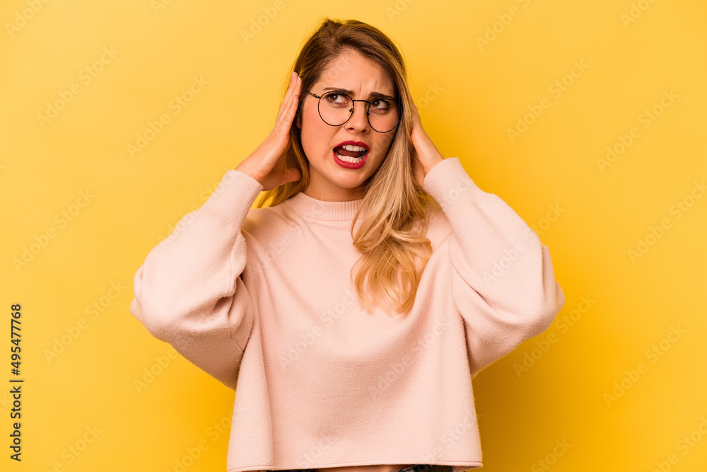 Young caucasian woman isolated on yellow background covering ears with hands trying not to hear too loud sound. Young caucasian woman isolated on yellow background covering ears with hands trying not to hear too loud sound.