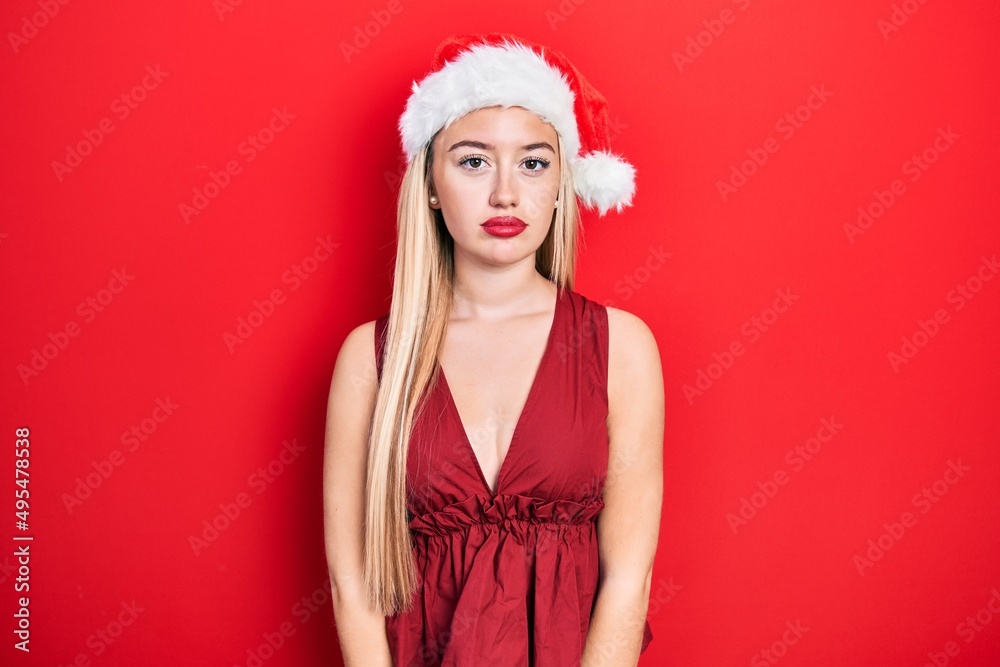Young blonde girl wearing christmas hat relaxed with serious expression on face. simple and natural looking at the camera. Young blonde girl wearing christmas hat relaxed with serious expression on face. simple and natural looking at the camera.
