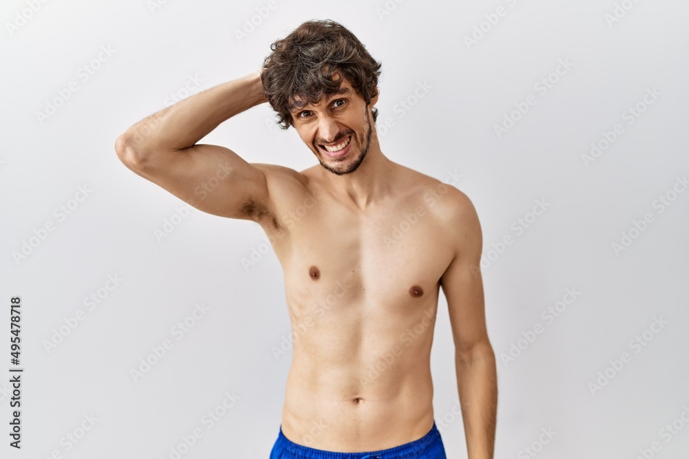Fototapeta premium Young hispanic man standing shirtless over isolated, background confuse and wonder about question. uncertain with doubt, thinking with hand on head. pensive concept.