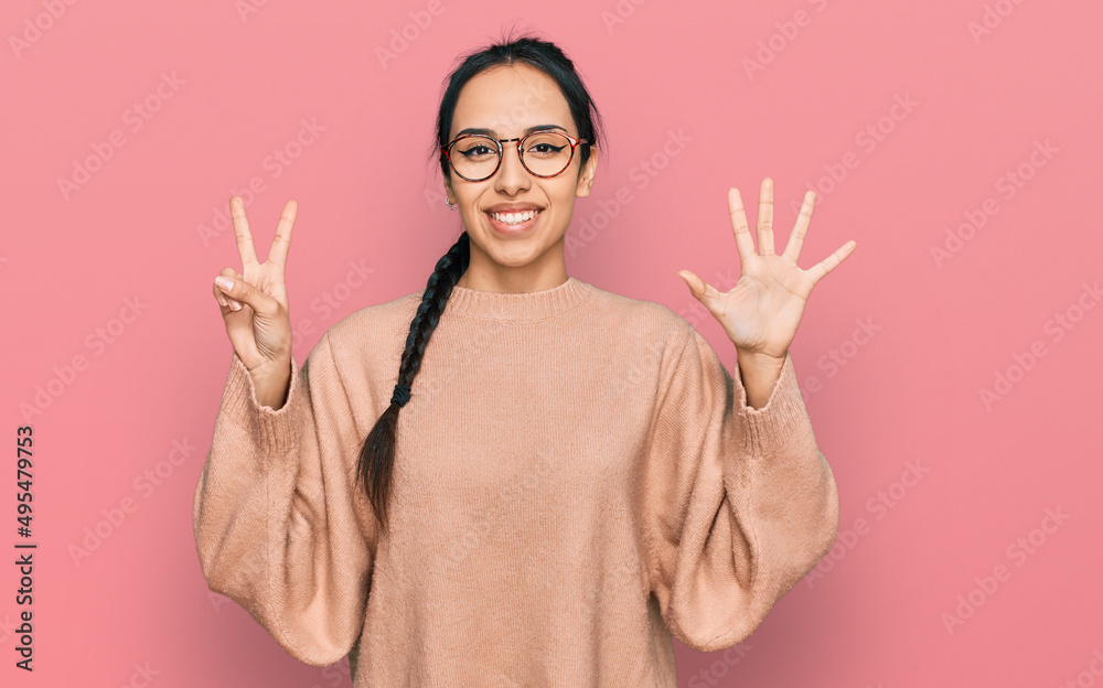 Young hispanic girl wearing casual clothes and glasses showing and pointing up with fingers number seven while smiling confident and happy. Young hispanic girl wearing casual clothes and glasses showing and pointing up with fingers number seven while smiling confident and happy.