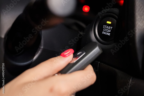 The car owner holds in his hand a remote control device for keyless entry near the start stop button