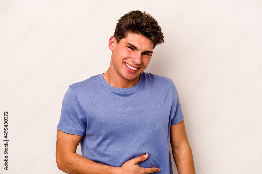 Obraz premium Young caucasian man isolated on white background touches tummy, smiles gently, eating and satisfaction concept.