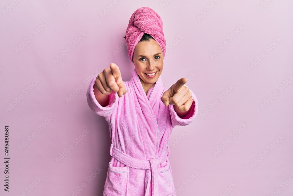 Young blonde woman wearing shower towel cap and bathrobe pointing to you and the camera with fingers, smiling positive and cheerful Young blonde woman wearing shower towel cap and bathrobe pointing to you and the camera with fingers, smiling positive and cheerful
