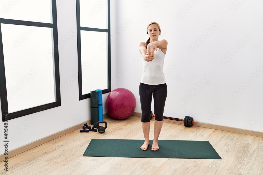 Young caucasian woman stretching at sport center