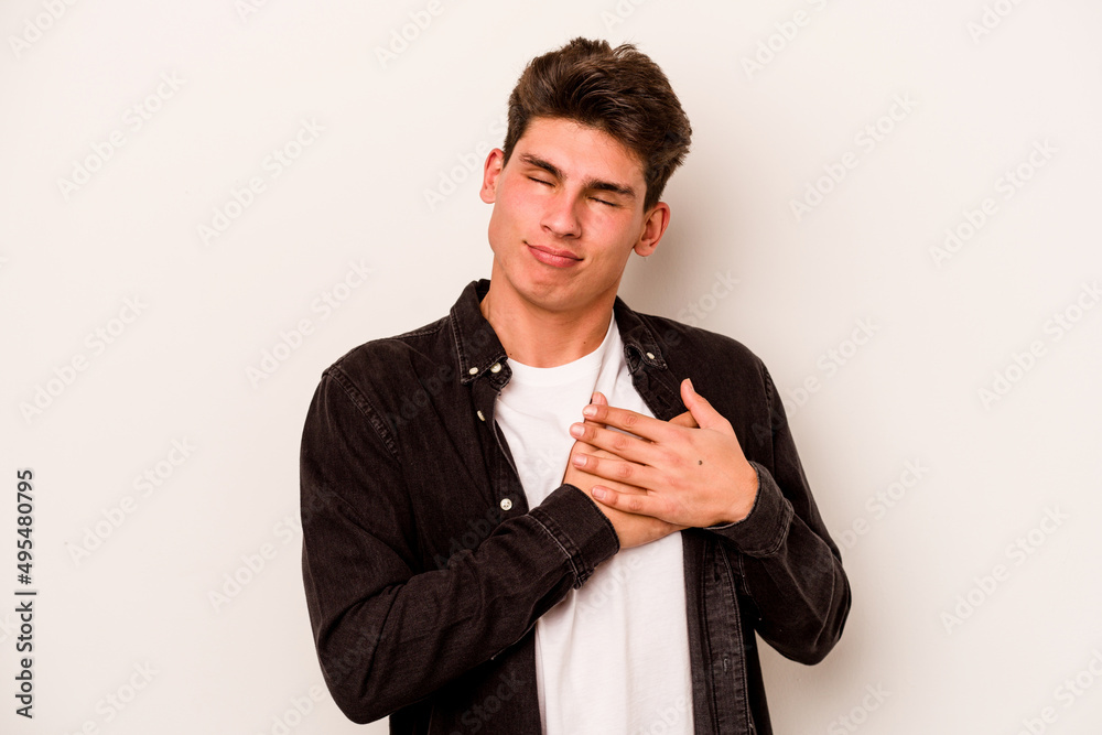 Young caucasian man isolated on white background has friendly expression, pressing palm to chest. Love concept. Young caucasian man isolated on white background has friendly expression, pressing palm to chest. Love concept.