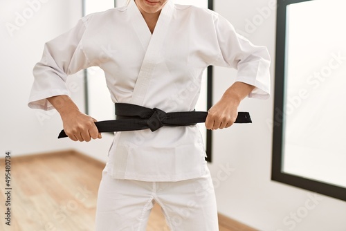 Young caucasian woman tying black karate belt at sport center