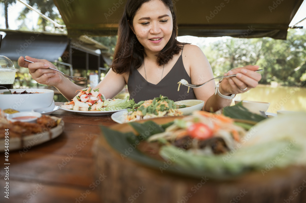 Asian woman eating healthy lunch at an outdoor restaurant during the day Relaxing urban lifestyle on weekends
