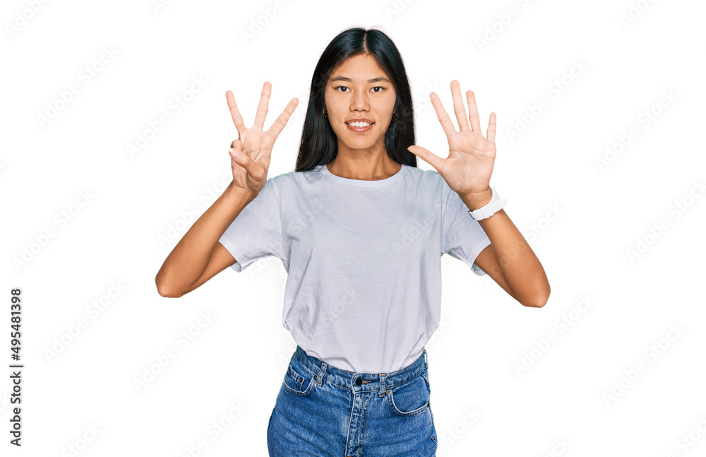 Beautiful young asian woman wearing casual white t shirt showing and pointing up with fingers number eight while smiling confident and happy. Beautiful young asian woman wearing casual white t shirt showing and pointing up with fingers number eight while smiling confident and happy.