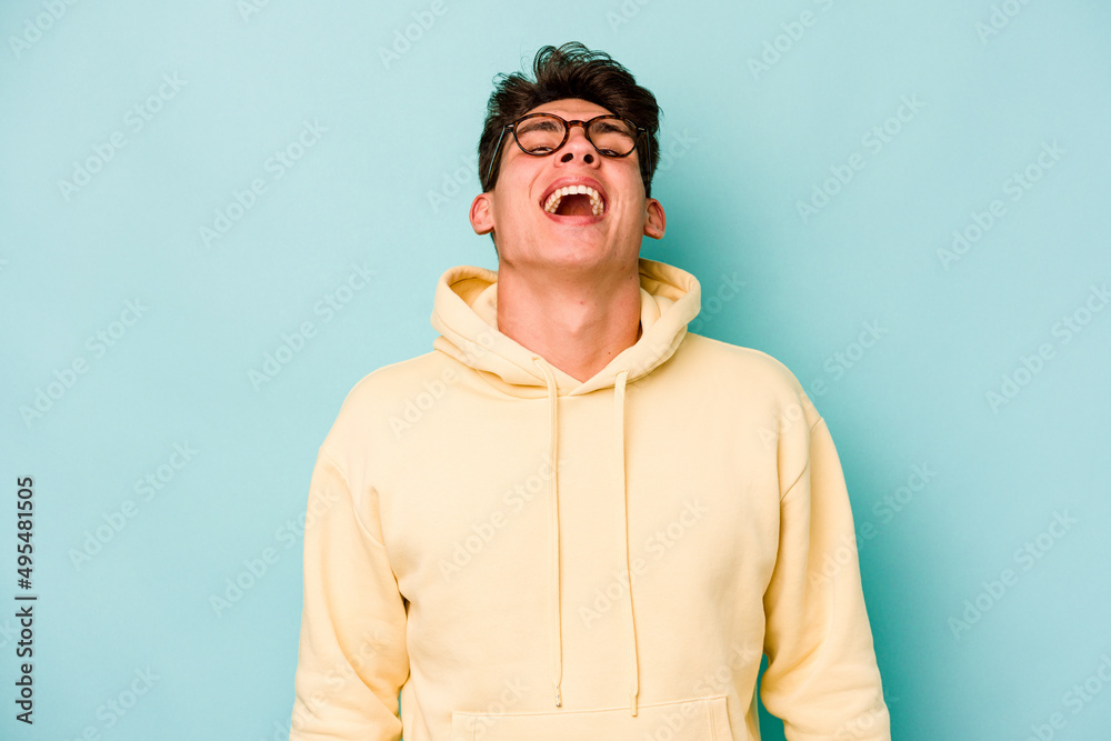 Fototapeta premium Young caucasian man isolated on blue background relaxed and happy laughing, neck stretched showing teeth.