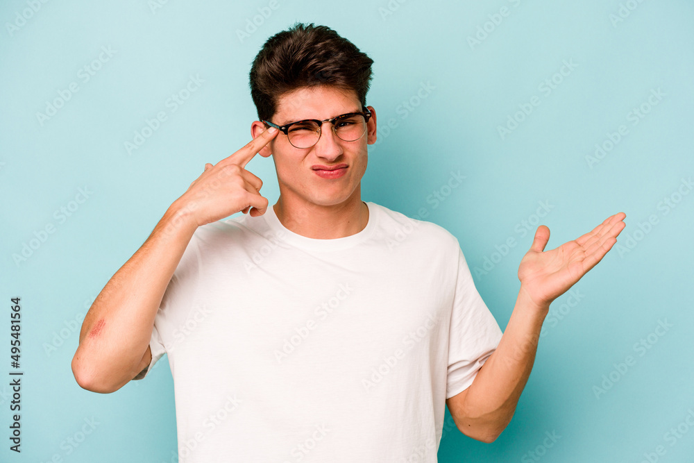 Young caucasian man isolated on blue background showing a disappointment gesture with forefinger. Young caucasian man isolated on blue background showing a disappointment gesture with forefinger.