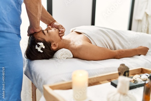 Latin man and woman wearing physiotherapy uniform having rehab session massaging head at beauty center