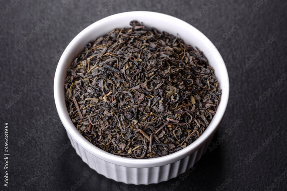 Tea green dry in white saucer on a dark concrete background Tea green dry in white saucer on a dark concrete background