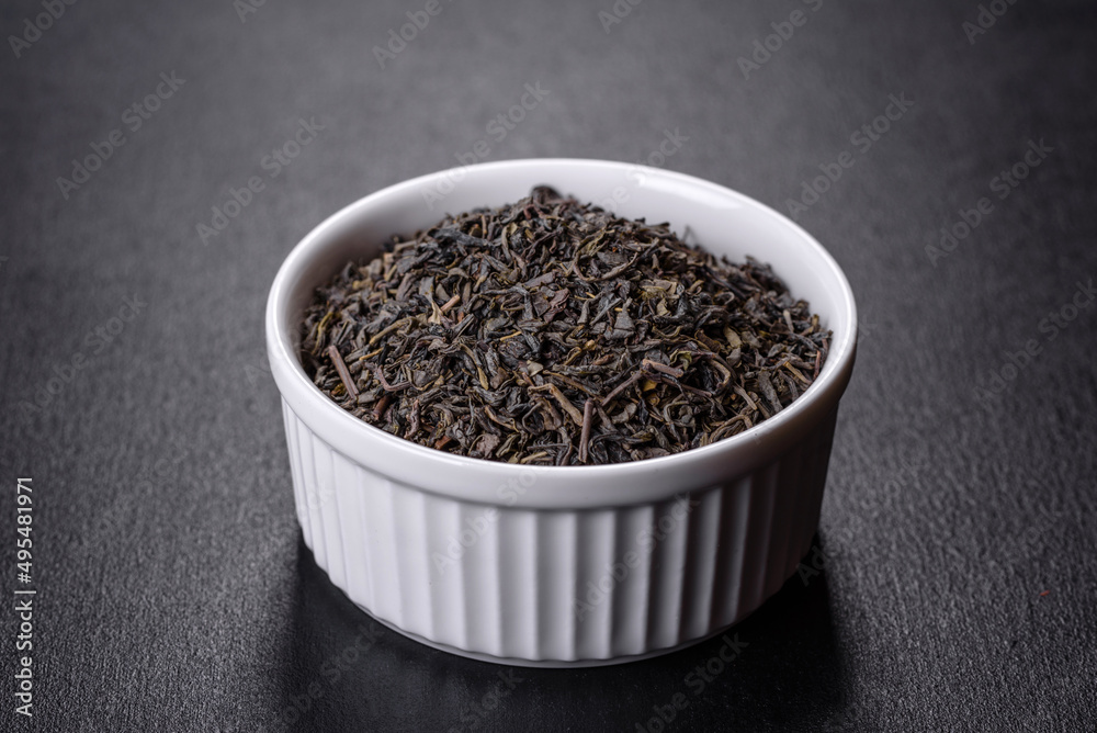 Tea green dry in white saucer on a dark concrete background Tea green dry in white saucer on a dark concrete background
