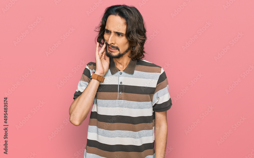 Young hispanic man wearing casual clothes touching mouth with hand with painful expression because of toothache or dental illness on teeth. dentist Young hispanic man wearing casual clothes touching mouth with hand with painful expression because of toothache or dental illness on teeth. dentist