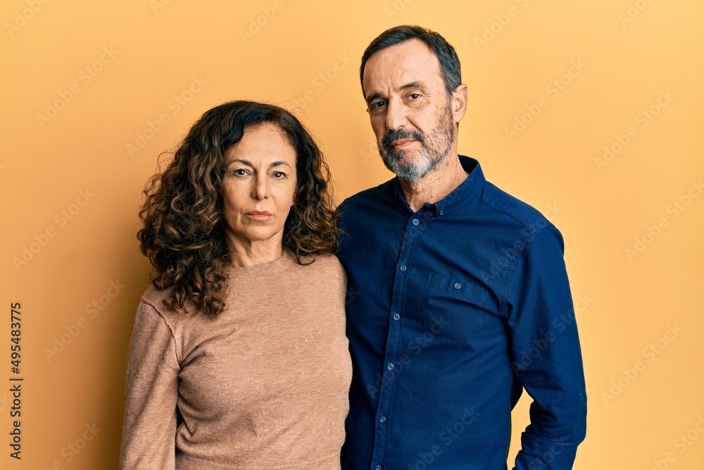 Middle age hispanic couple wearing casual clothes relaxed with serious expression on face. simple and natural looking at the camera. Middle age hispanic couple wearing casual clothes relaxed with serious expression on face. simple and natural looking at the camera.