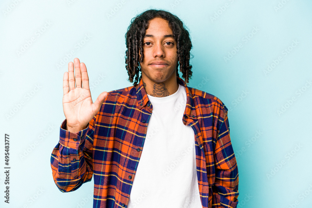 Young African American man isolated on blue background smiling cheerful showing number five with fingers. Young African American man isolated on blue background smiling cheerful showing number five with fingers.