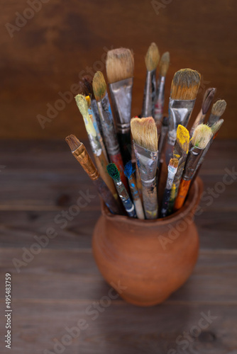 Paint brush in clay jug at wooden table background texture. Paintbrush for painting