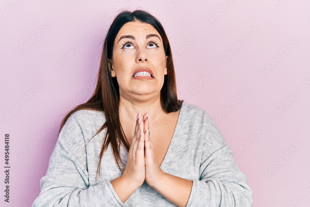 Fototapeta premium Young hispanic woman wearing casual clothes begging and praying with hands together with hope expression on face very emotional and worried. begging.