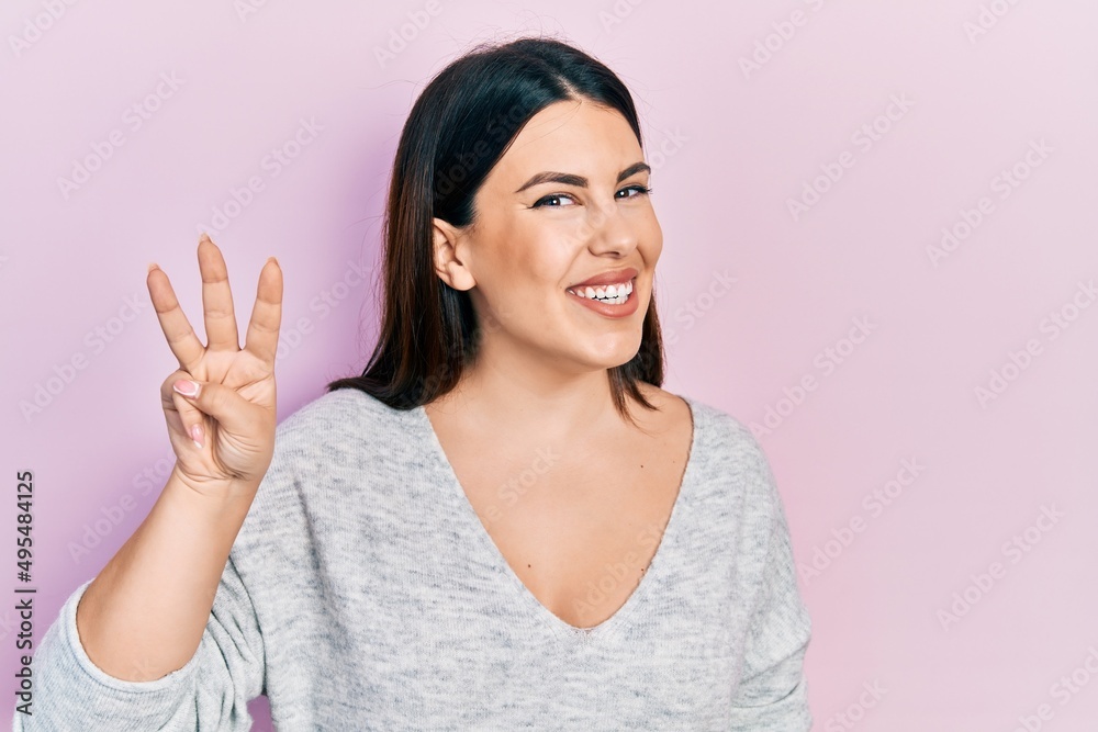 Young hispanic woman wearing casual clothes showing and pointing up with fingers number three while smiling confident and happy.