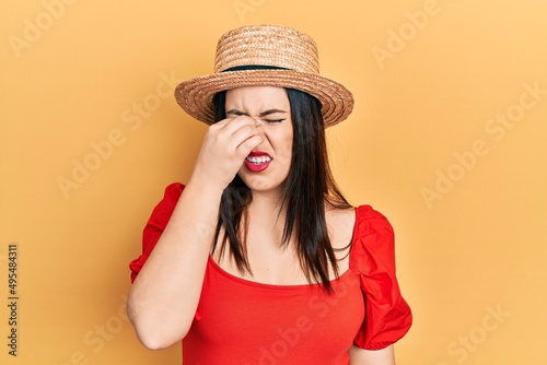 Young hispanic woman wearing summer hat tired rubbing nose and eyes feeling fatigue and headache. stress and frustration concept.