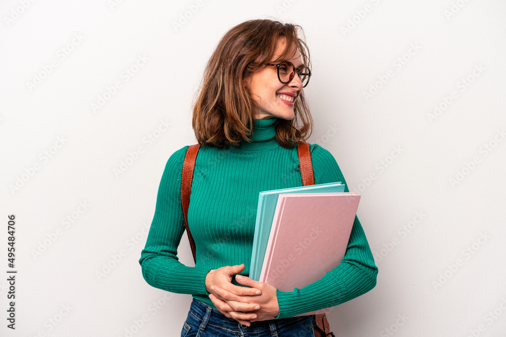 Young student caucasian woman isolated on white background looks aside smiling, cheerful and pleasant. Young student caucasian woman isolated on white background looks aside smiling, cheerful and pleasant.