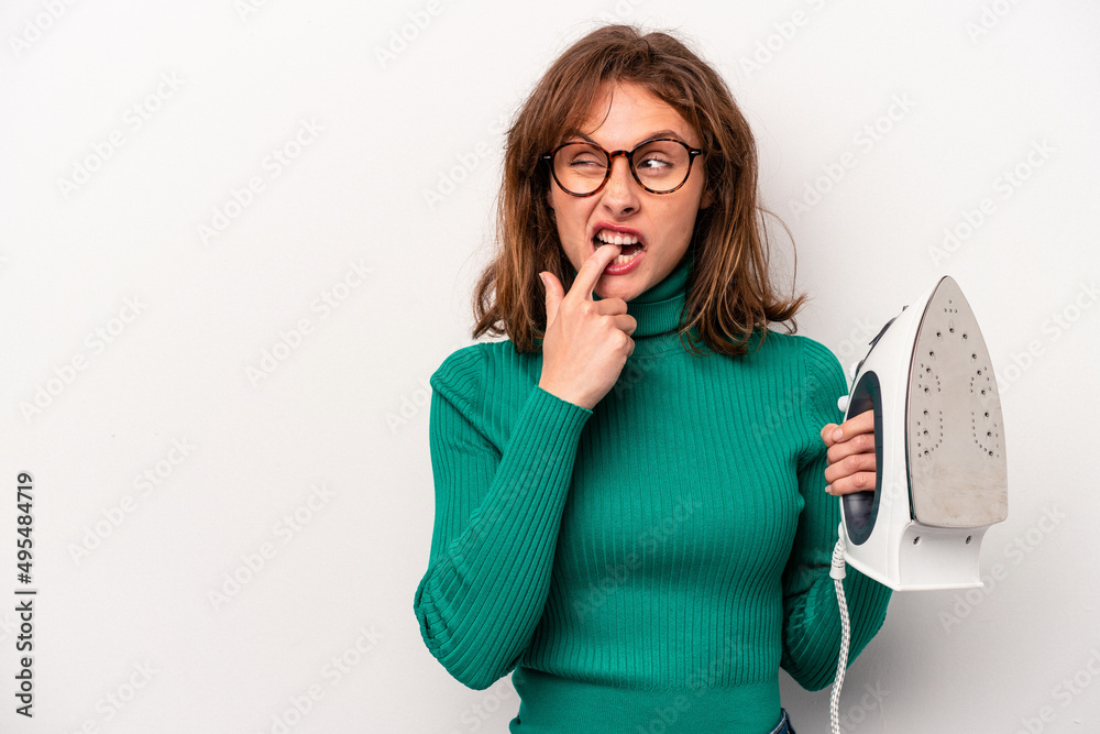 Young caucasian woman holding iron isolated on white background relaxed thinking about something looking at a copy space.