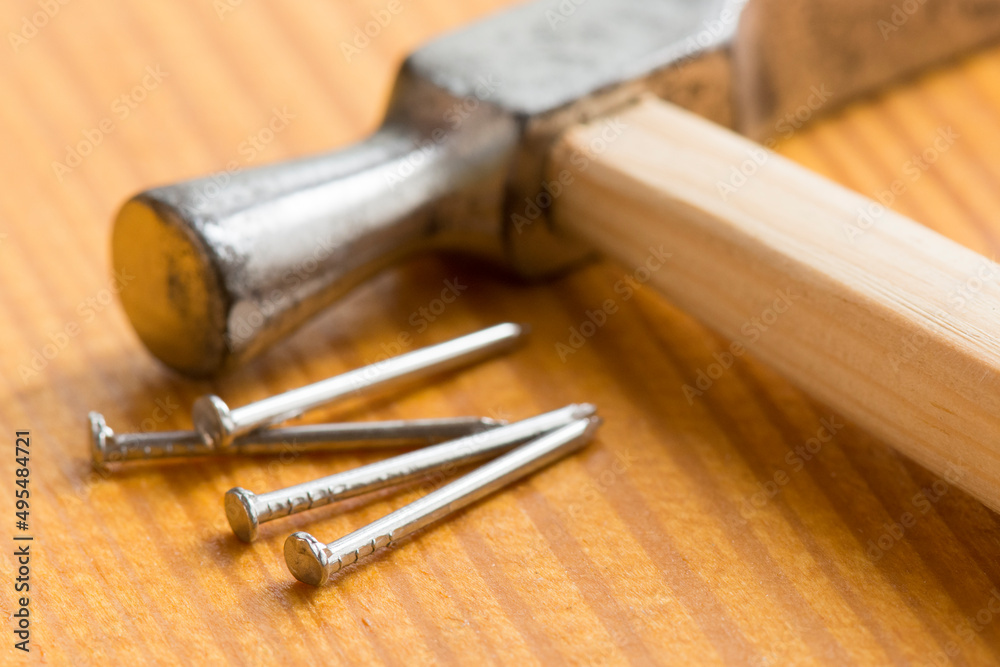 Carpenter hammer and small nails on a wooden worktable. Handmade master. Small carpentry work in the workshop. Home renovation. Carpenter hammer and small nails on a wooden worktable. Handmade master. Small carpentry work in the workshop. Home renovation.