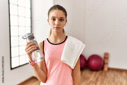 Young brunette teenager wearing sportswear holding water bottle skeptic and nervous, frowning upset because of problem. negative person.