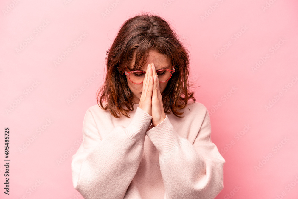 Young caucasian woman isolated on pink background praying, showing devotion, religious person looking for divine inspiration. Young caucasian woman isolated on pink background praying, showing devotion, religious person looking for divine inspiration.