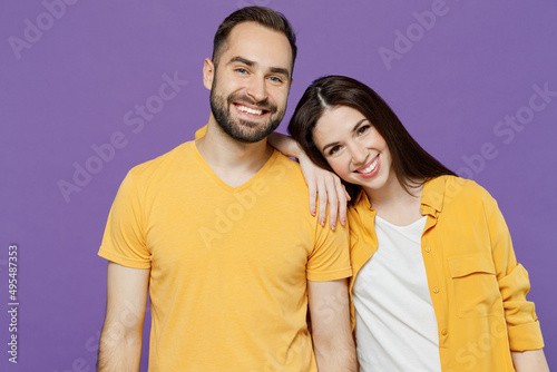 Young happy smiling nice lovely couple two friends family man woman 20s together wear yellow casual clothes looking camera hud put head on shoulder isolated on plain violet background studio portrait