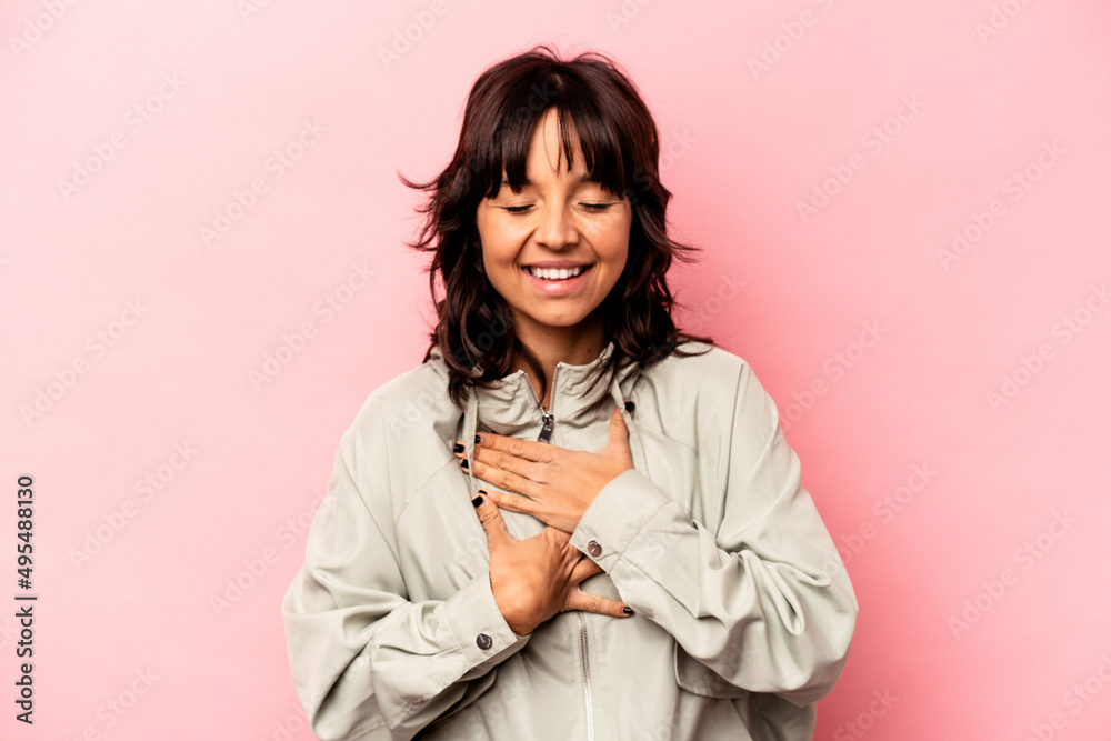 Young hispanic woman isolated on pink background laughs happily and has fun keeping hands on stomach. Young hispanic woman isolated on pink background laughs happily and has fun keeping hands on stomach.