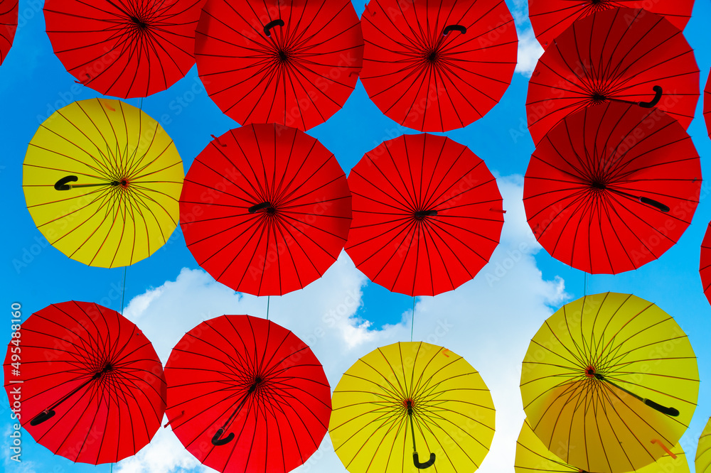 Umbrella background. Multicolored parasols hanging in sky bottom- up. Street decoration