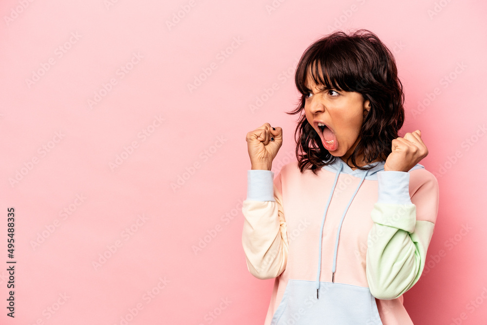 Fototapeta premium Young hispanic woman isolated on pink background raising fist after a victory, winner concept.