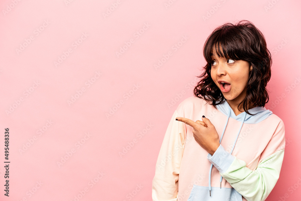 Young hispanic woman isolated on pink background points with thumb finger away, laughing and carefree. Young hispanic woman isolated on pink background points with thumb finger away, laughing and carefree.