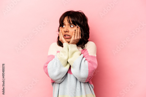Young hispanic woman isolated on pink background scared and afraid.